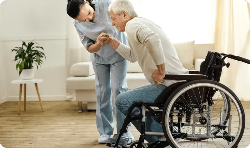 Nurse holding a senior passenger's hand as he rises from his wheelchair